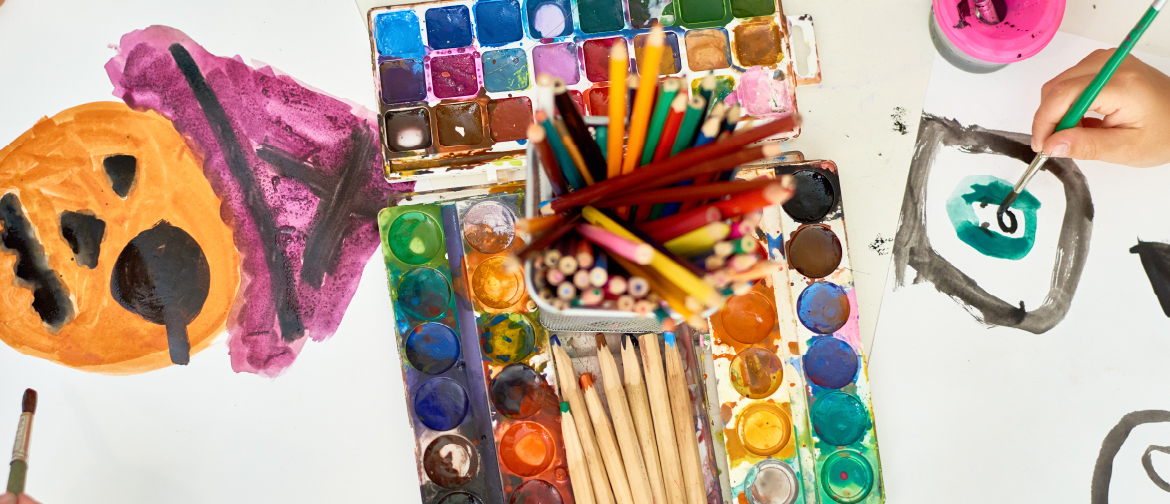 birds eye view photograph of art materials and kids creating halloween themed artworks