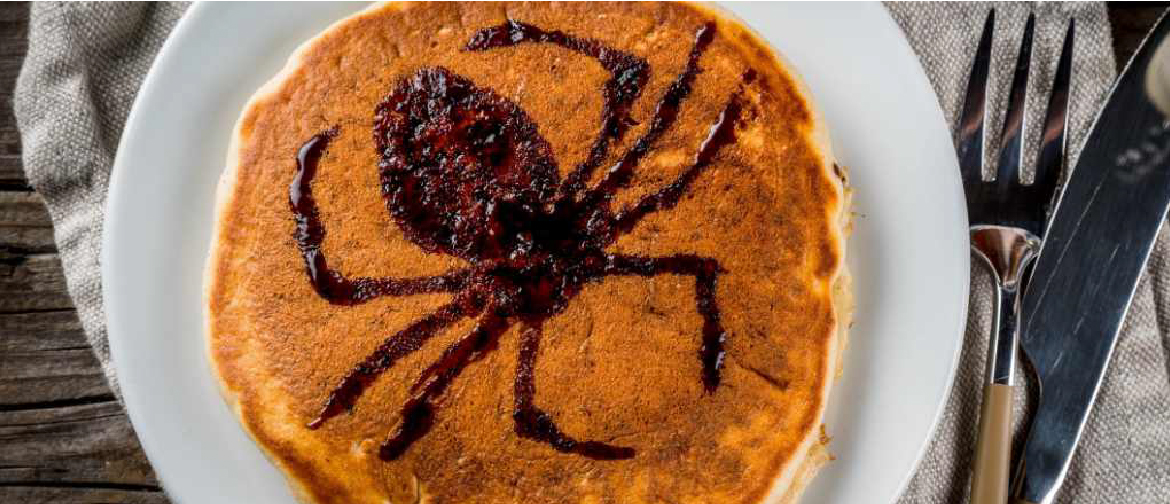 photograph of a stack of pancakes with a halloween decoration