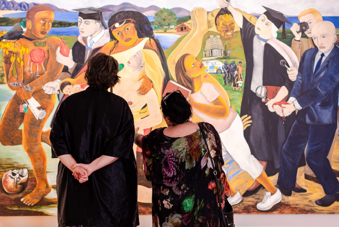 Photograph of two women looking up at a painting by New Zealand artist, Robyn Kahukiwa