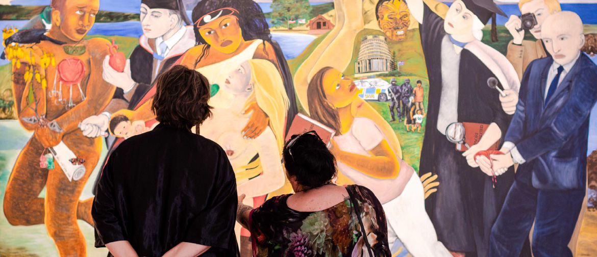 Photograph of two women looking up at a painting by New Zealand artist, Robyn Kahukiwa